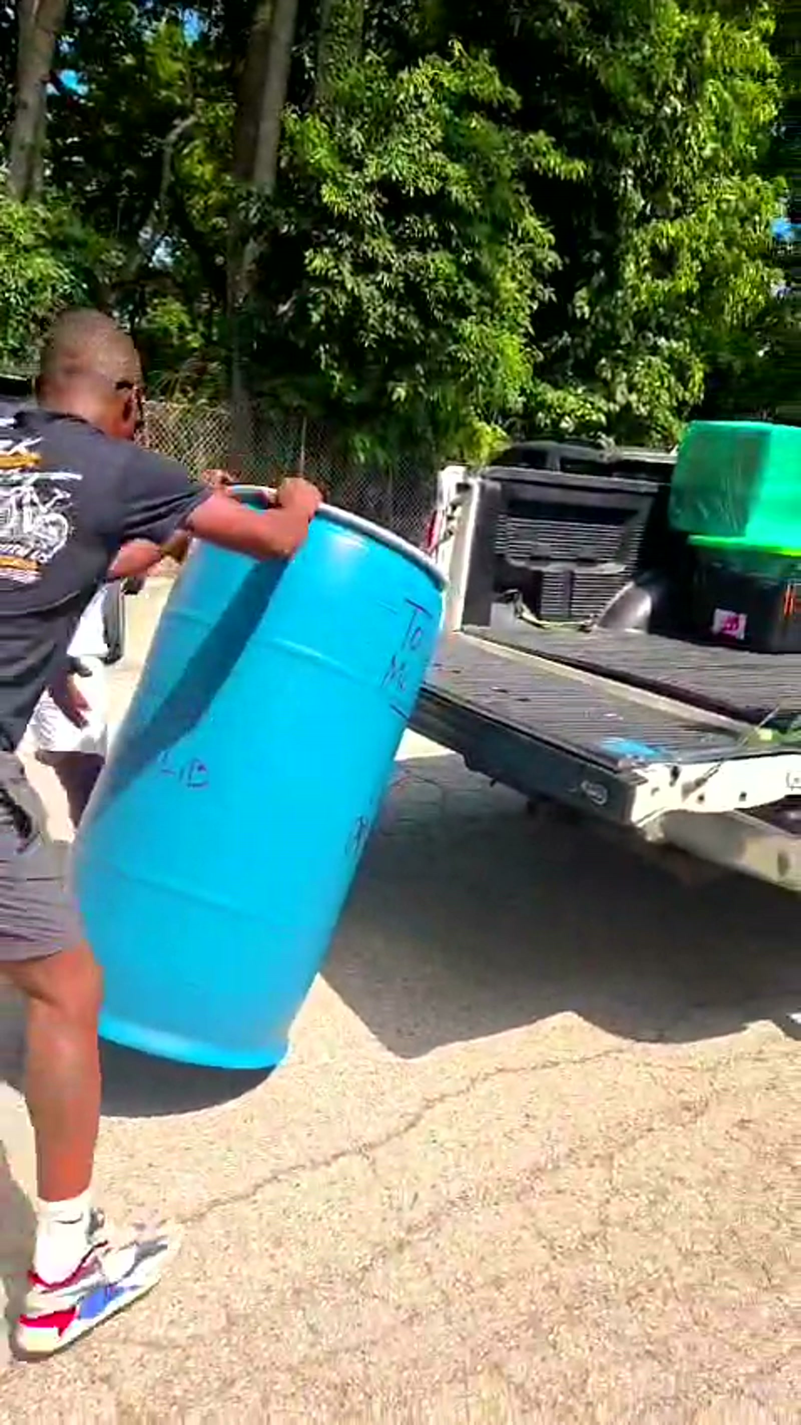 KC loading a blue customer barrel onto the pickup truck
